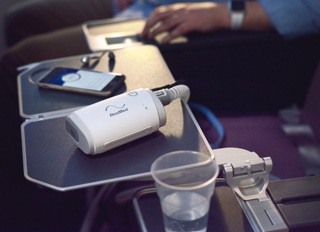 ResMed AirMini travel CPAP machine on an aeroplane tray table
